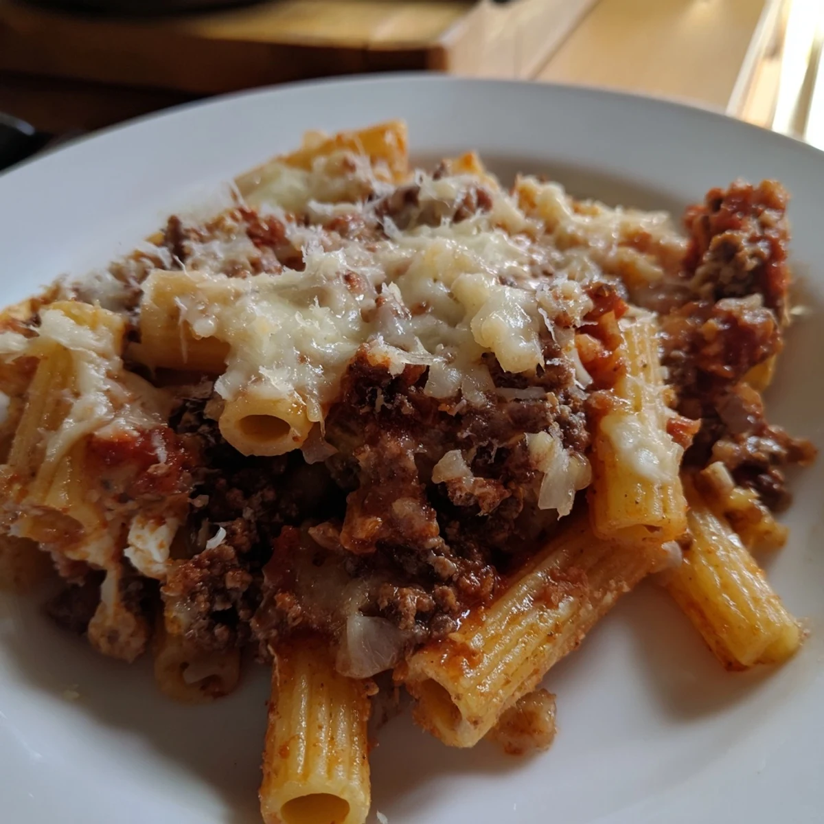 Serving of Baked Ziti with Ground Beef and Marinara plated next to fresh basil leaves, ready to be enjoyed with garlic bread.