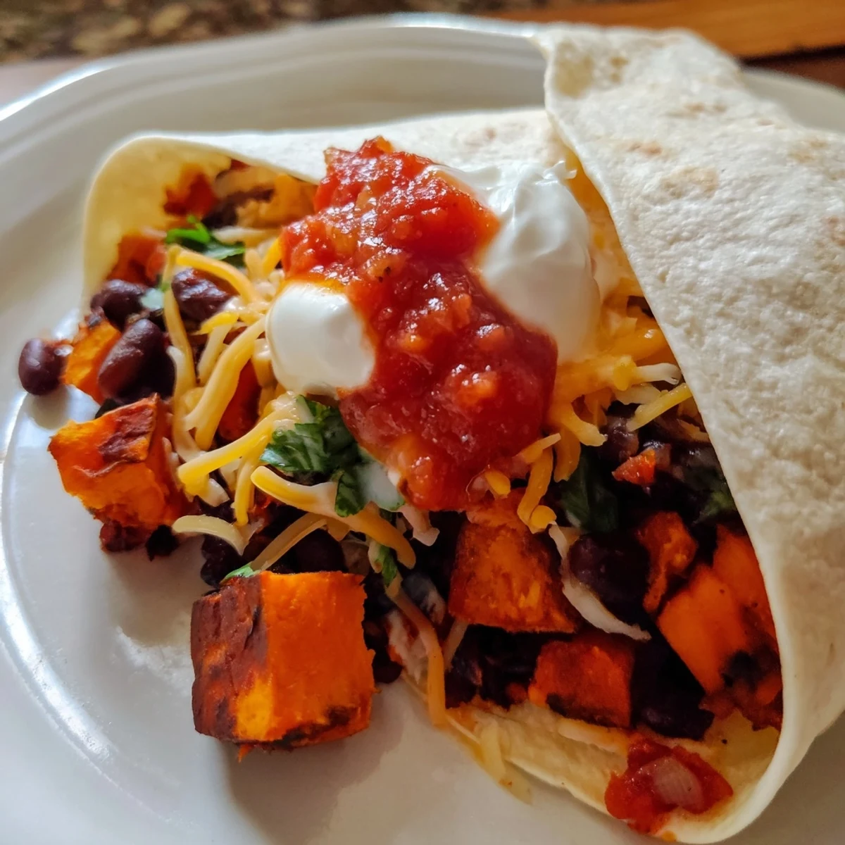 Golden-brown roasted sweet potatoes and black beans stuffed into a warm flour tortilla for Roasted Sweet Potato and Black Bean Burritos.