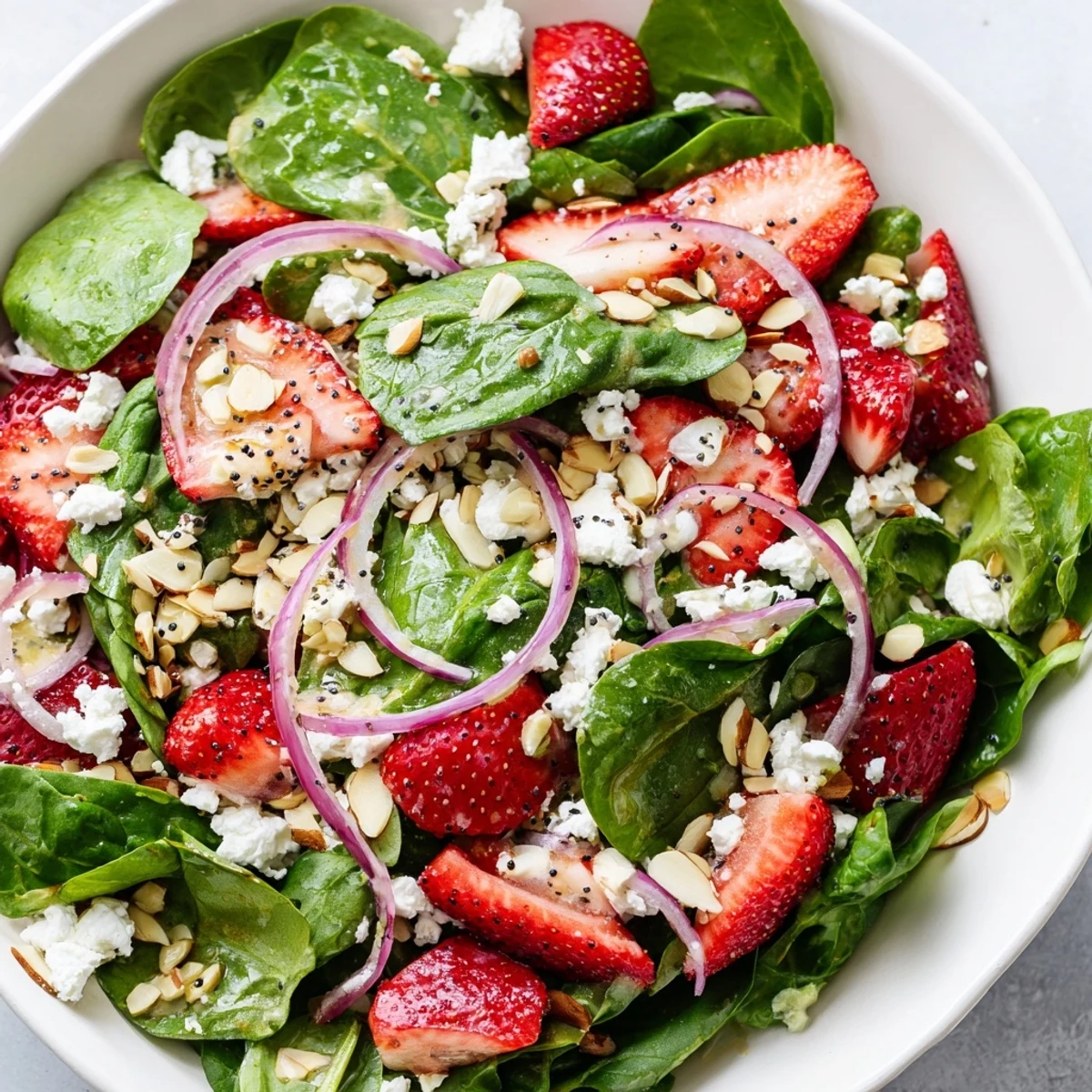 Served as a light vegetarian main course, this refreshing strawberry spinach salad features crisp vegetables, sweet fruit, and nutty crunch for summer gatherings.