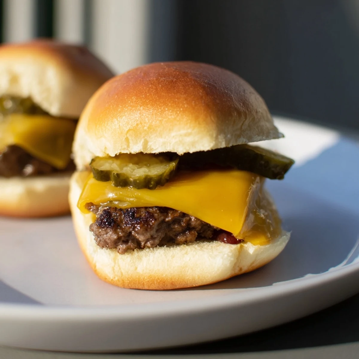 Sizzling beef sliders with cheese and pickles are stacked high, perfect for a casual backyard party spread.