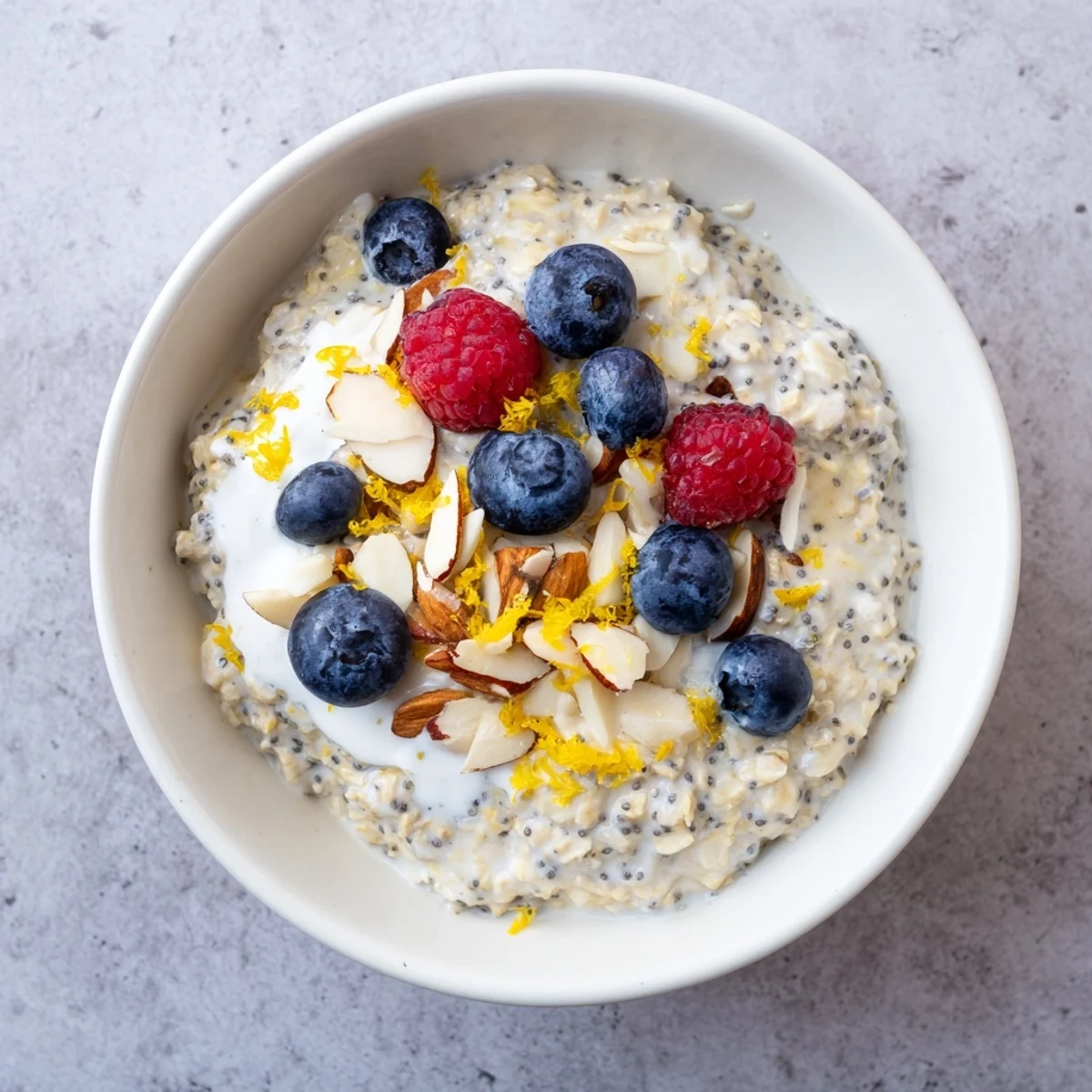 This vegan lemon poppy seed overnight oats recipe shows creamy oats topped with fresh berries and sliced almonds.