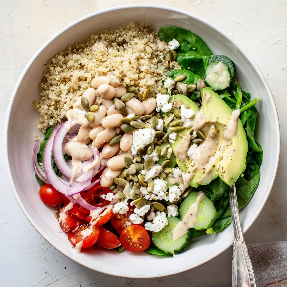 A vibrant close-up of the Spinach & White Bean Ultimate Protein Power Bowl showcasing fluffy quinoa, fresh greens, and creamy avocado slices.