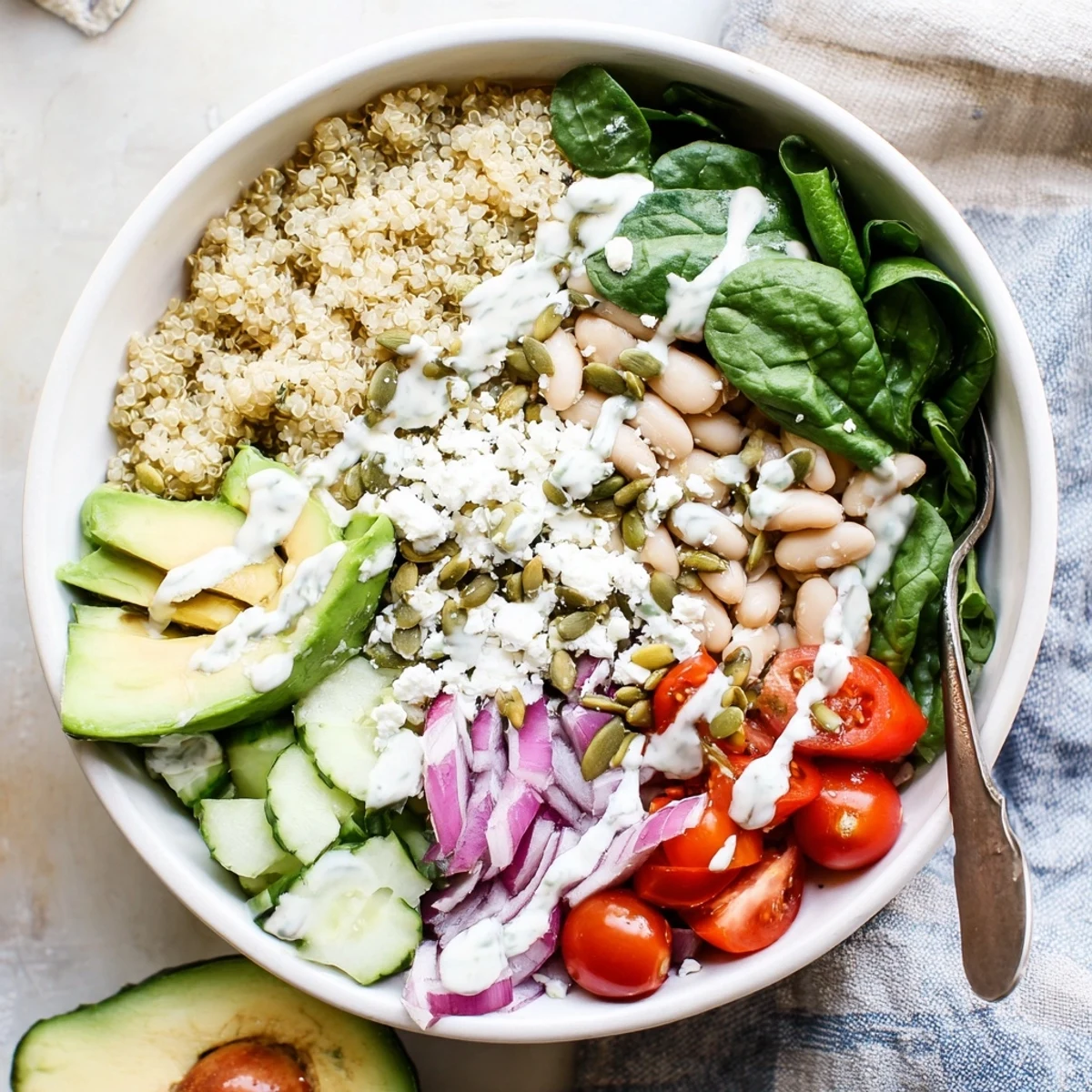 The Spinach & White Bean Ultimate Protein Power Bowl sits ready to eat with drizzled lemon-tahini dressing and toasted pumpkin seeds.