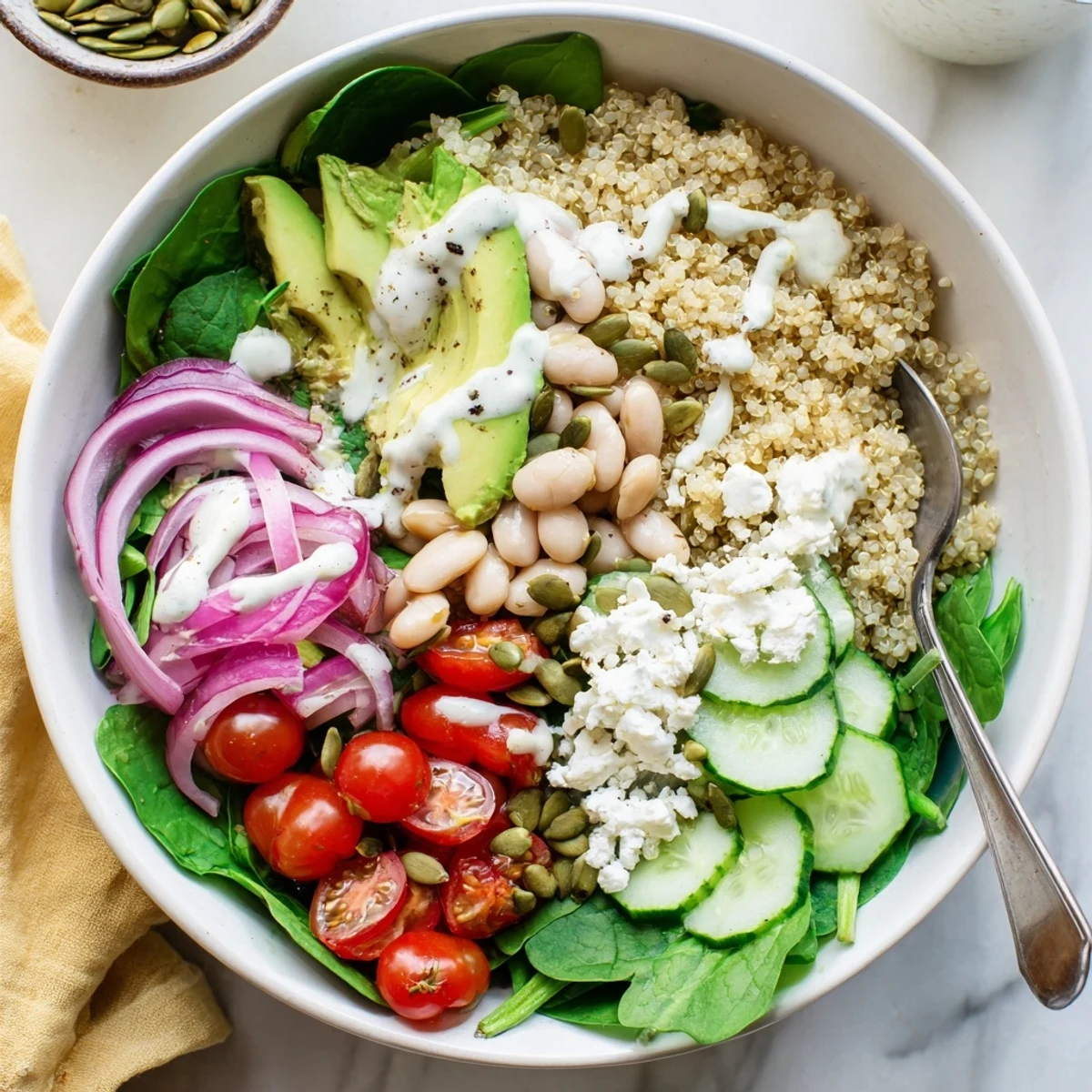 Serve this Spinach & White Bean Ultimate Protein Power Bowl for lunch, featuring white beans, cherry tomatoes, and a tangy dressing.