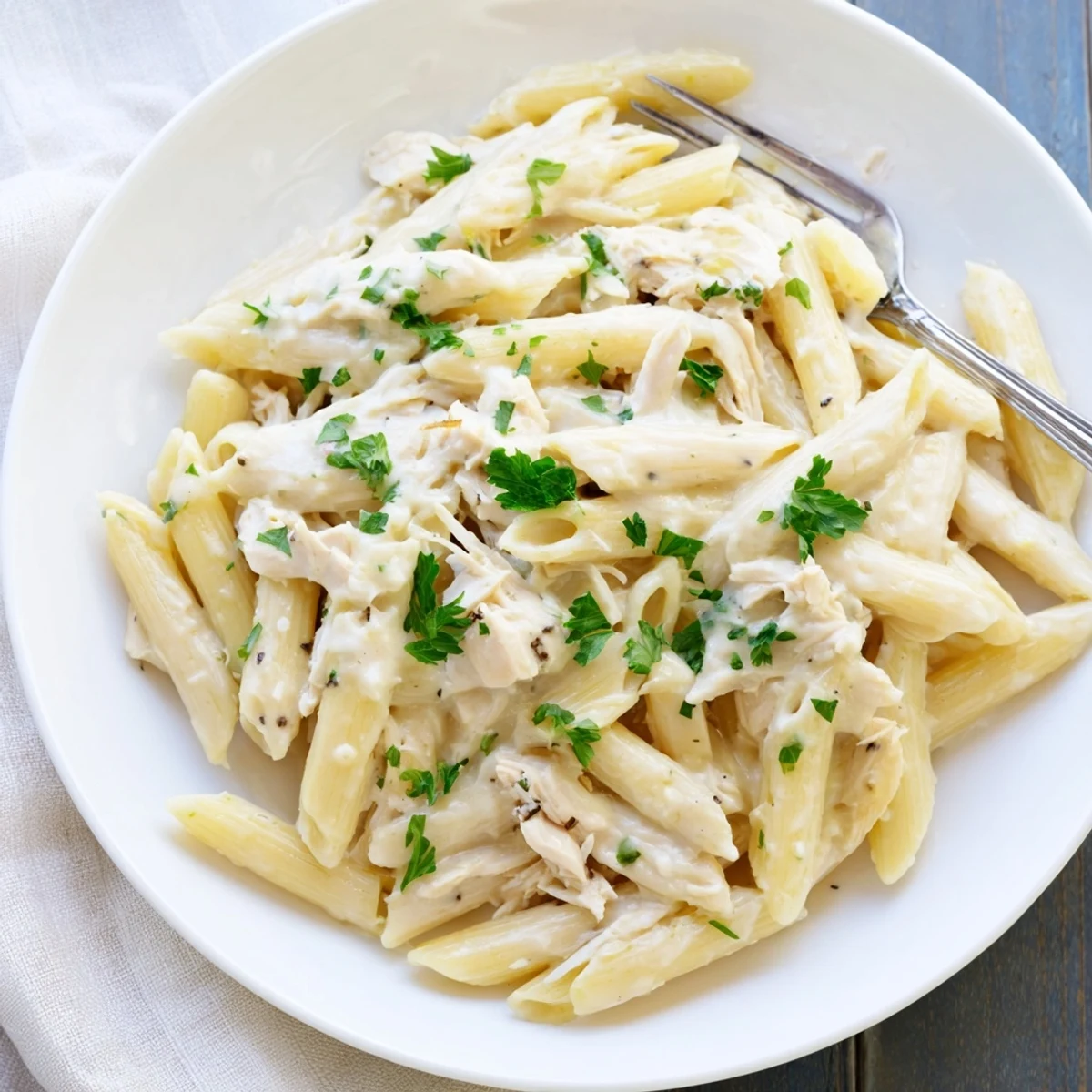 Tender chicken and creamy sauce in Crockpot Garlic Parmesan Chicken Pasta, served with penne in a warm crockpot.
