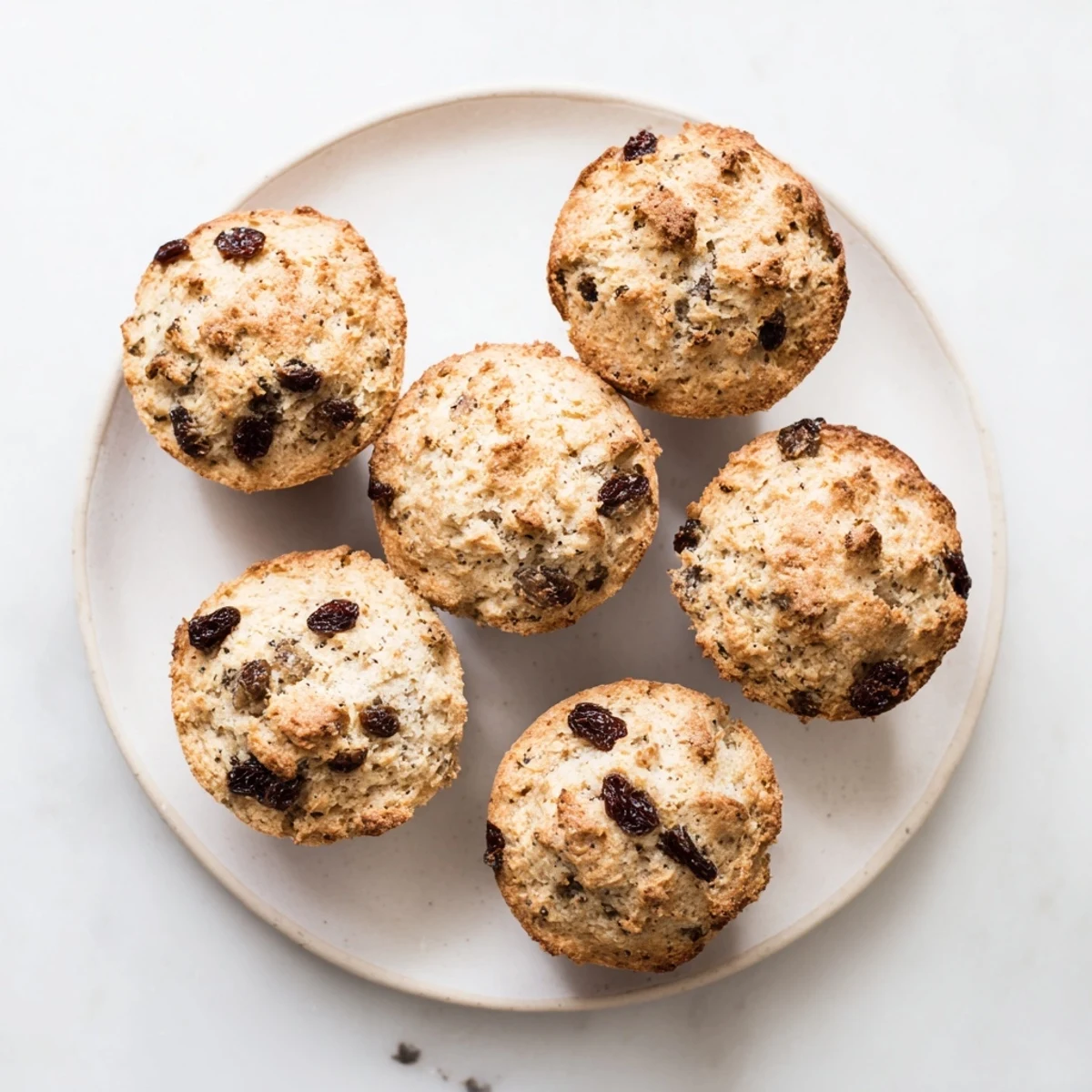 Freshly baked Irish Soda Bread Muffins with a crispy golden crust sit on a rustic wooden board.