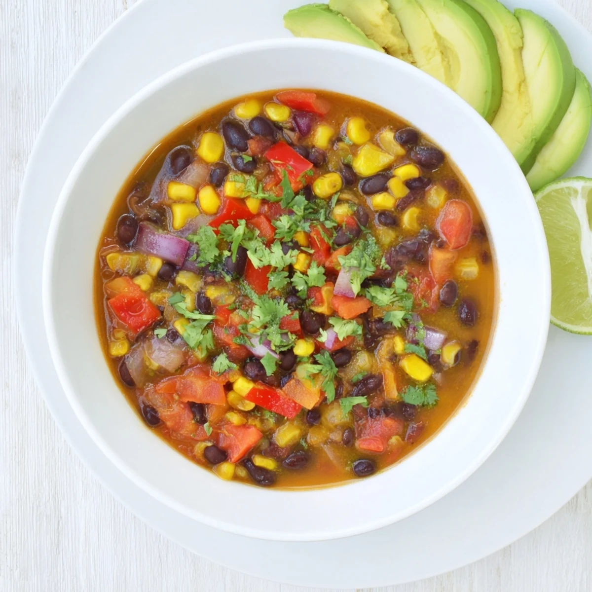 A hearty, vibrant vegan chili with black beans and sweet corn served in a rustic earthenware bowl.