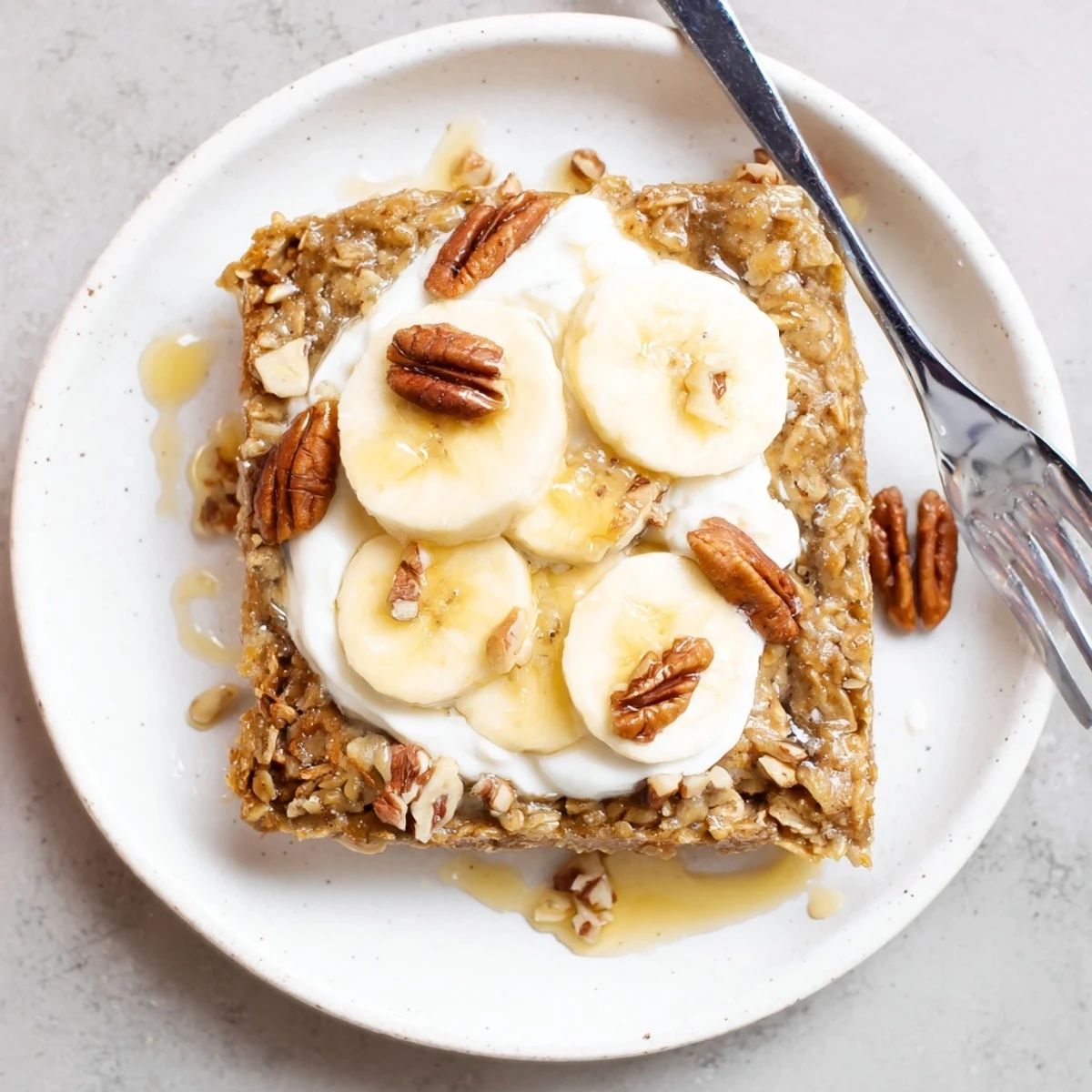 Golden-brown Banana Baked Oatmeal with Greek Yogurt topped with sliced bananas and walnuts, a cozy breakfast bake fresh from the oven.
