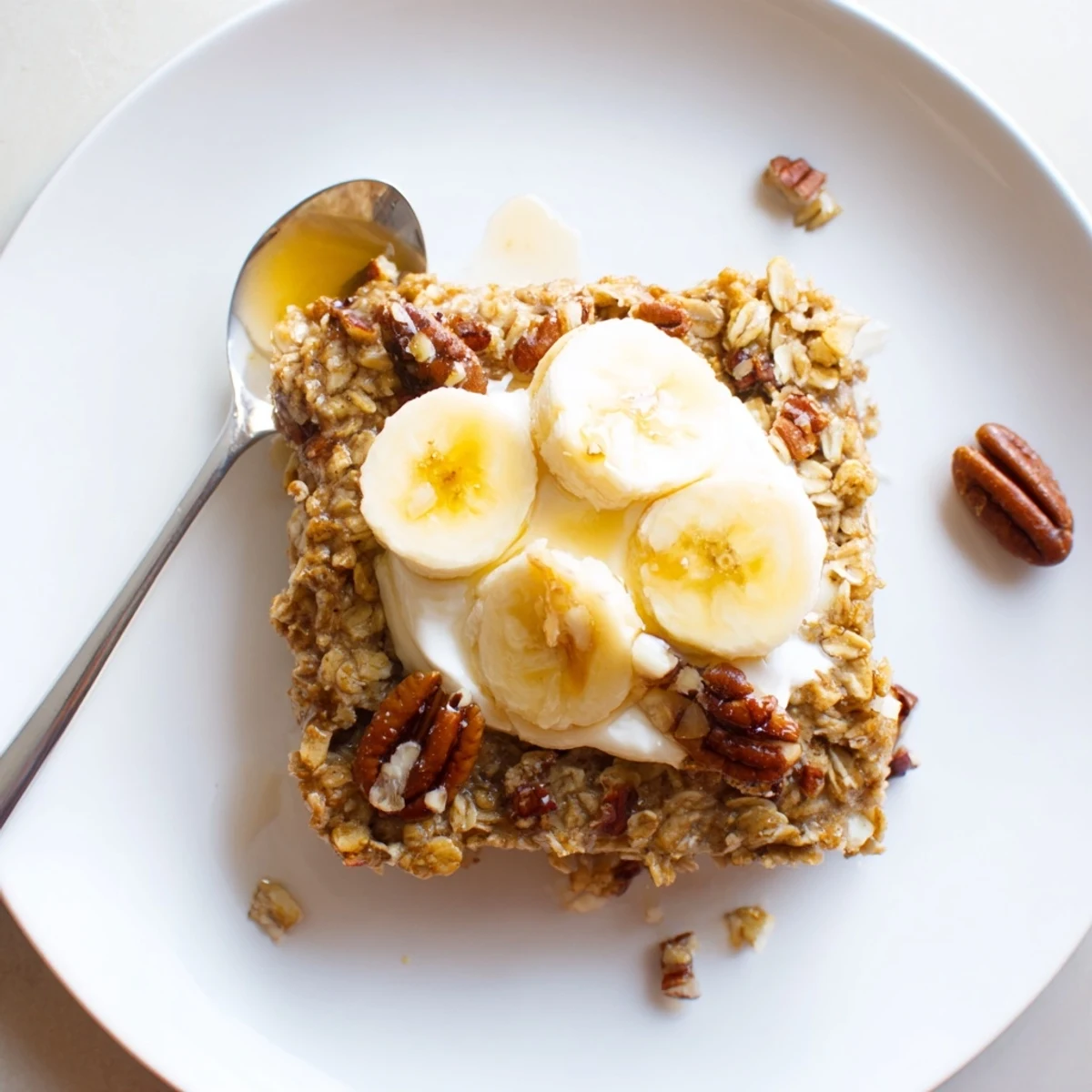 Banana Baked Oatmeal with Greek Yogurt cooled on a wooden board, showing fluffy oats, banana slices, and a nutty crunchy topping.