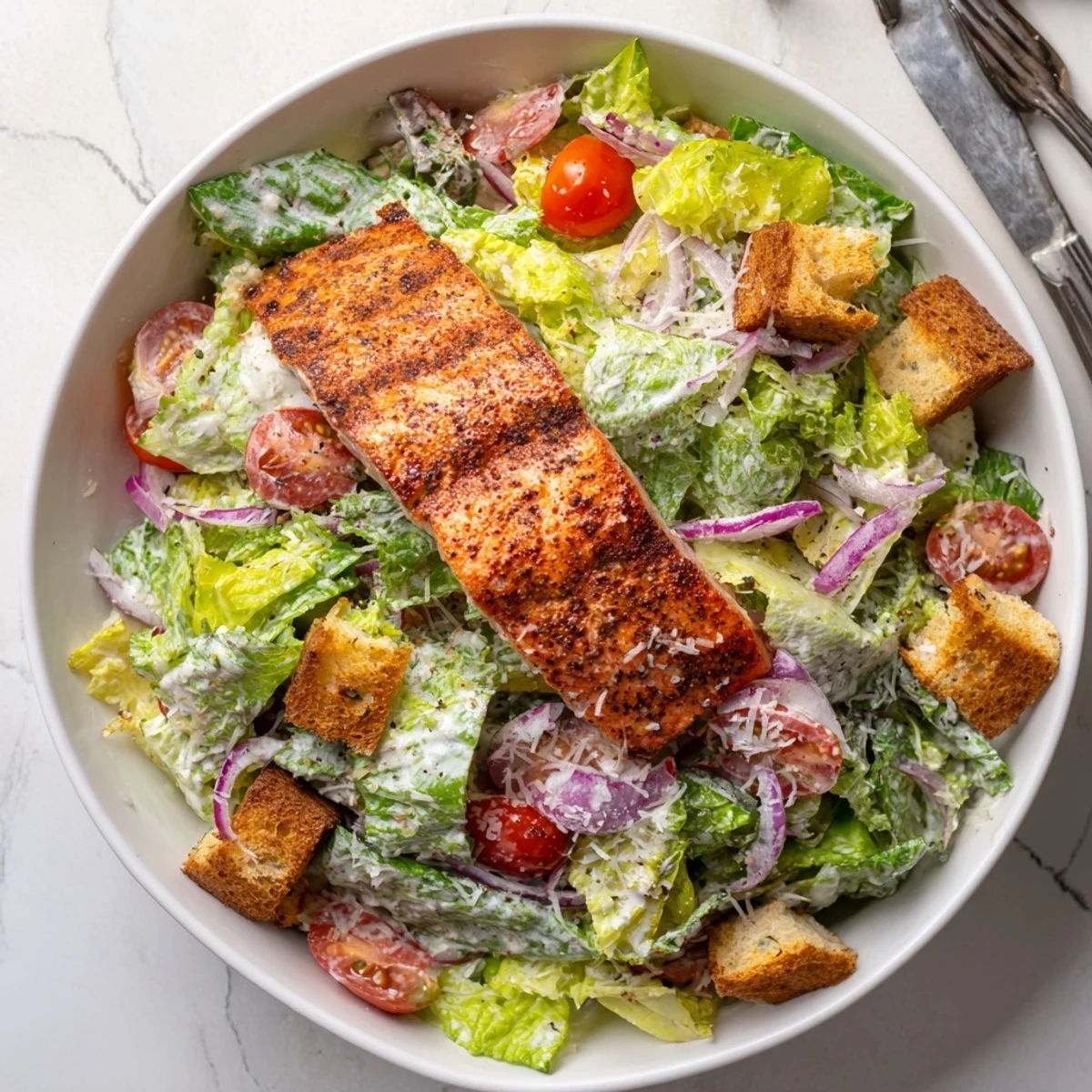Golden grilled salmon fillet rests atop crisp romaine Caesar salad with cherry tomatoes and crunchy croutons