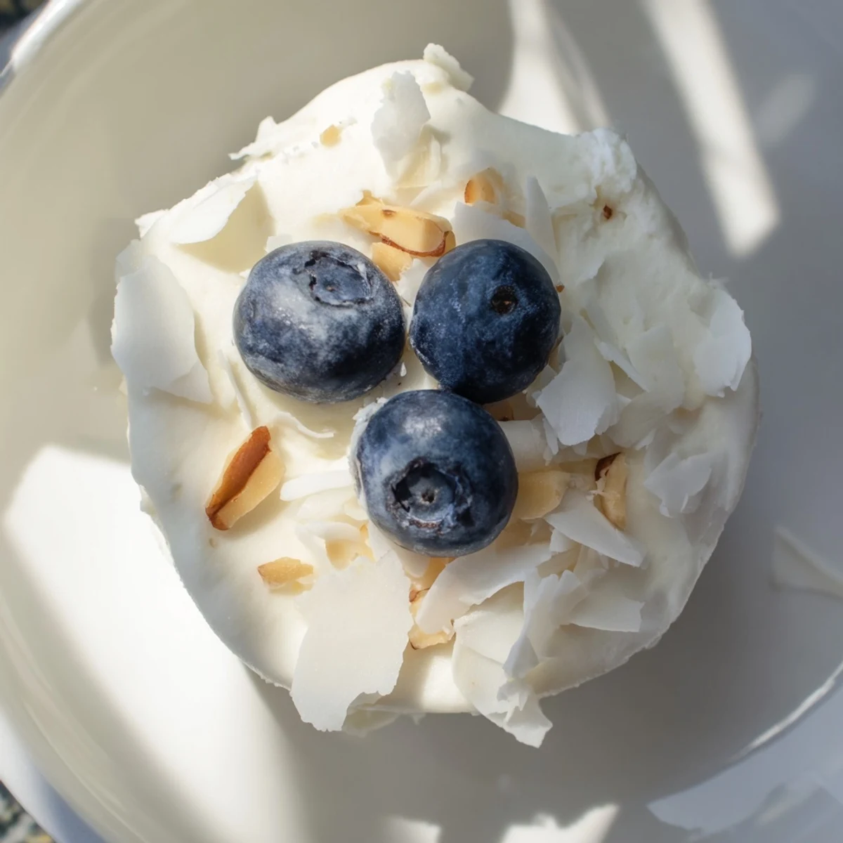 Fresh blueberry Greek yogurt bites arranged on a white plate with scattered blueberries and coconut garnish
