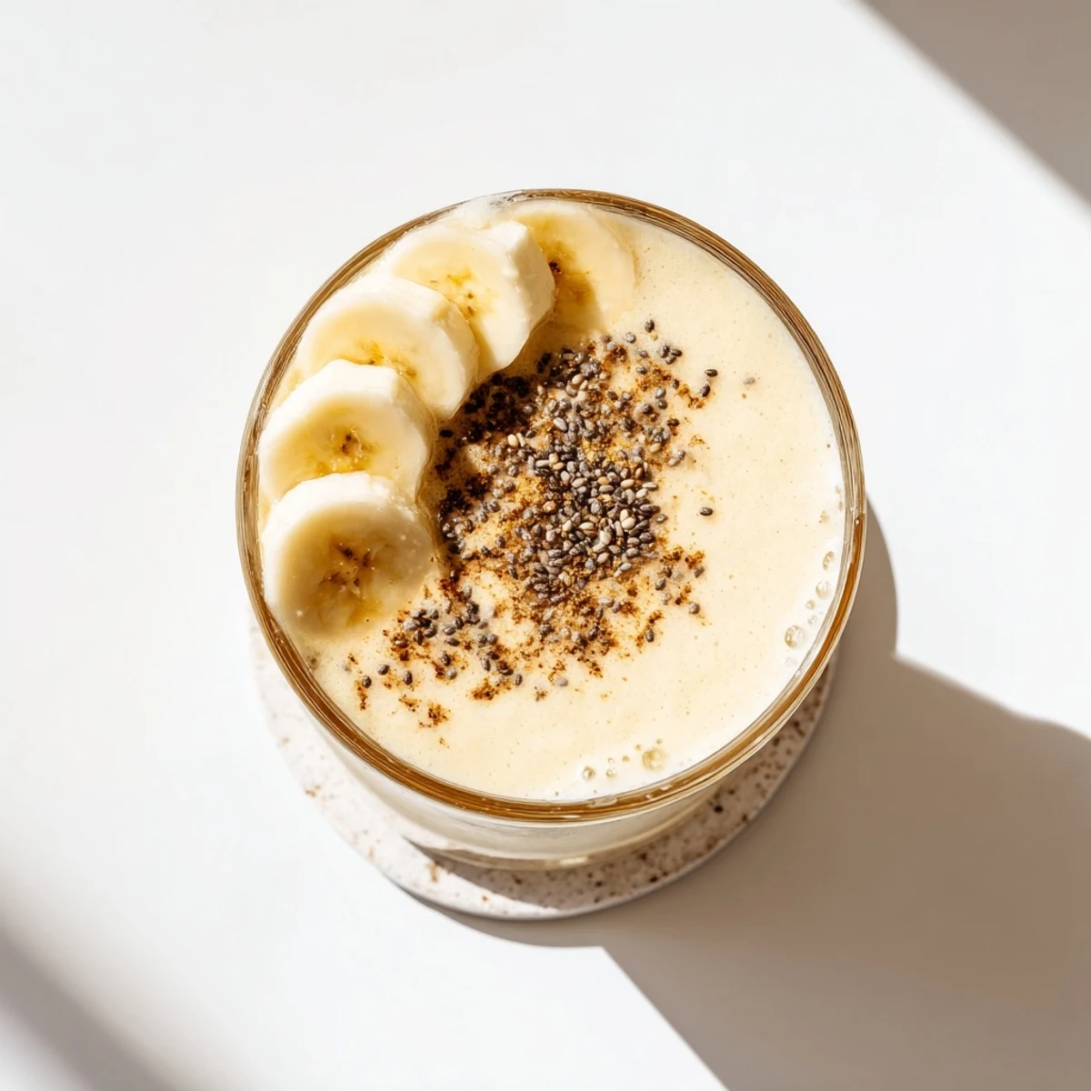 Creamy Greek yogurt banana smoothie poured into tall glasses topped with fresh banana slices
