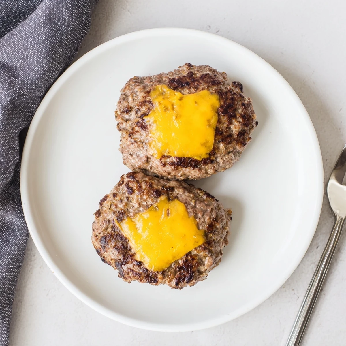 Golden brown air fryer hamburger patties sizzling hot with melted cheese on toasted buns