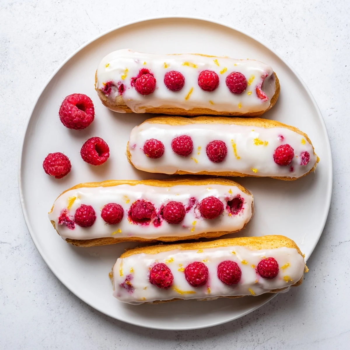 French pastry éclairs split open showing fluffy lemon cream filling topped with fresh red raspberries