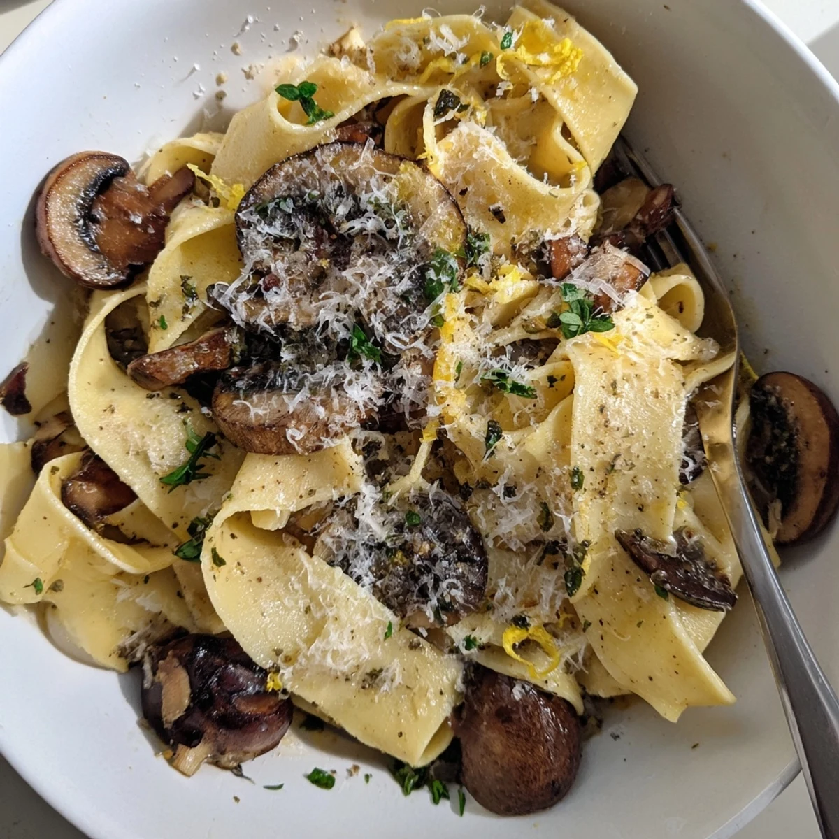 Creamy garlic butter mushroom pappardelle pasta topped with grated Parmesan and fresh herbs