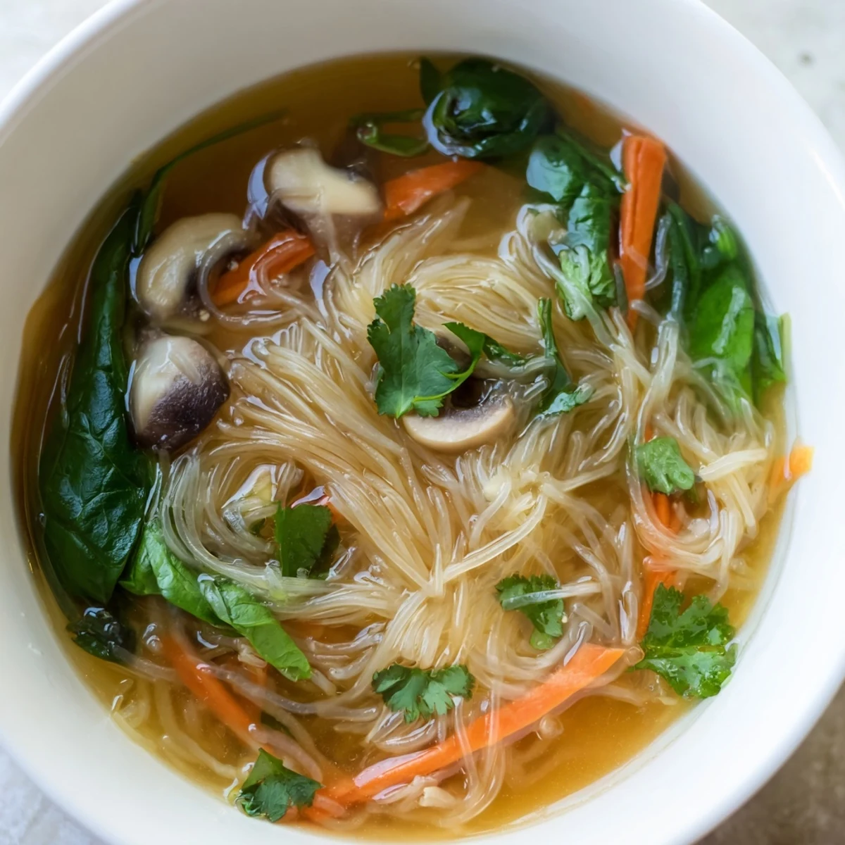 Comforting vegan broth with ginger, garlic, and rice noodles topped with lime wedges