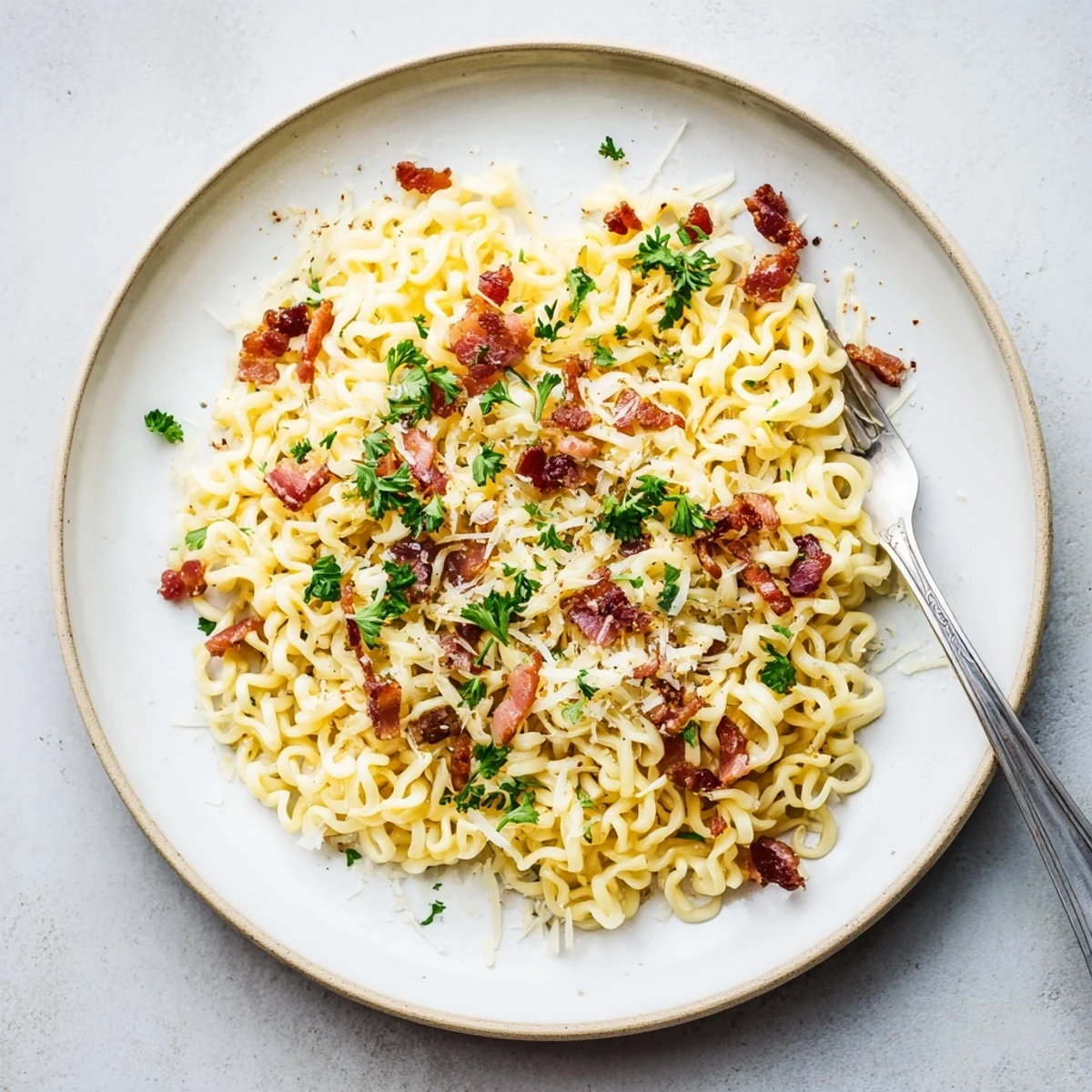 Creamy ramen carbonara with crispy bacon and silky egg parmesan sauce in a white bowl