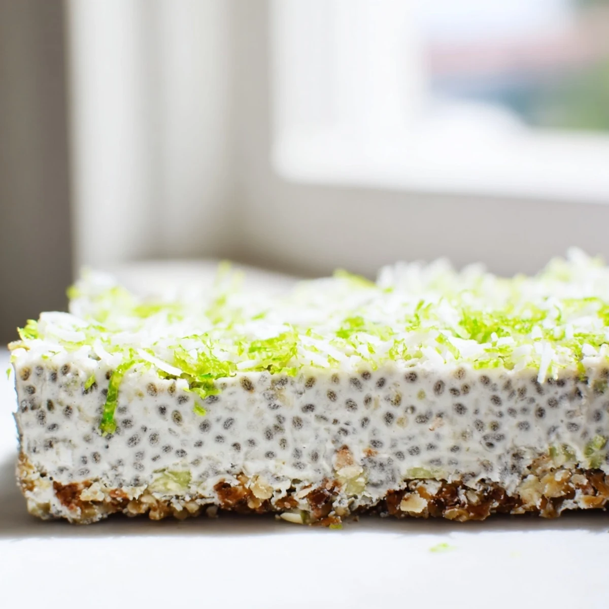 Creamy no-bake coconut lime chia pudding bars topped with toasted coconut shreds and fresh green lime zest