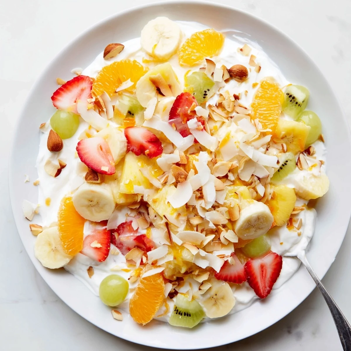 Refreshing creamy fruit salad with diced kiwi, mandarin oranges, and sliced bananas drizzled with sweet vanilla cream sauce