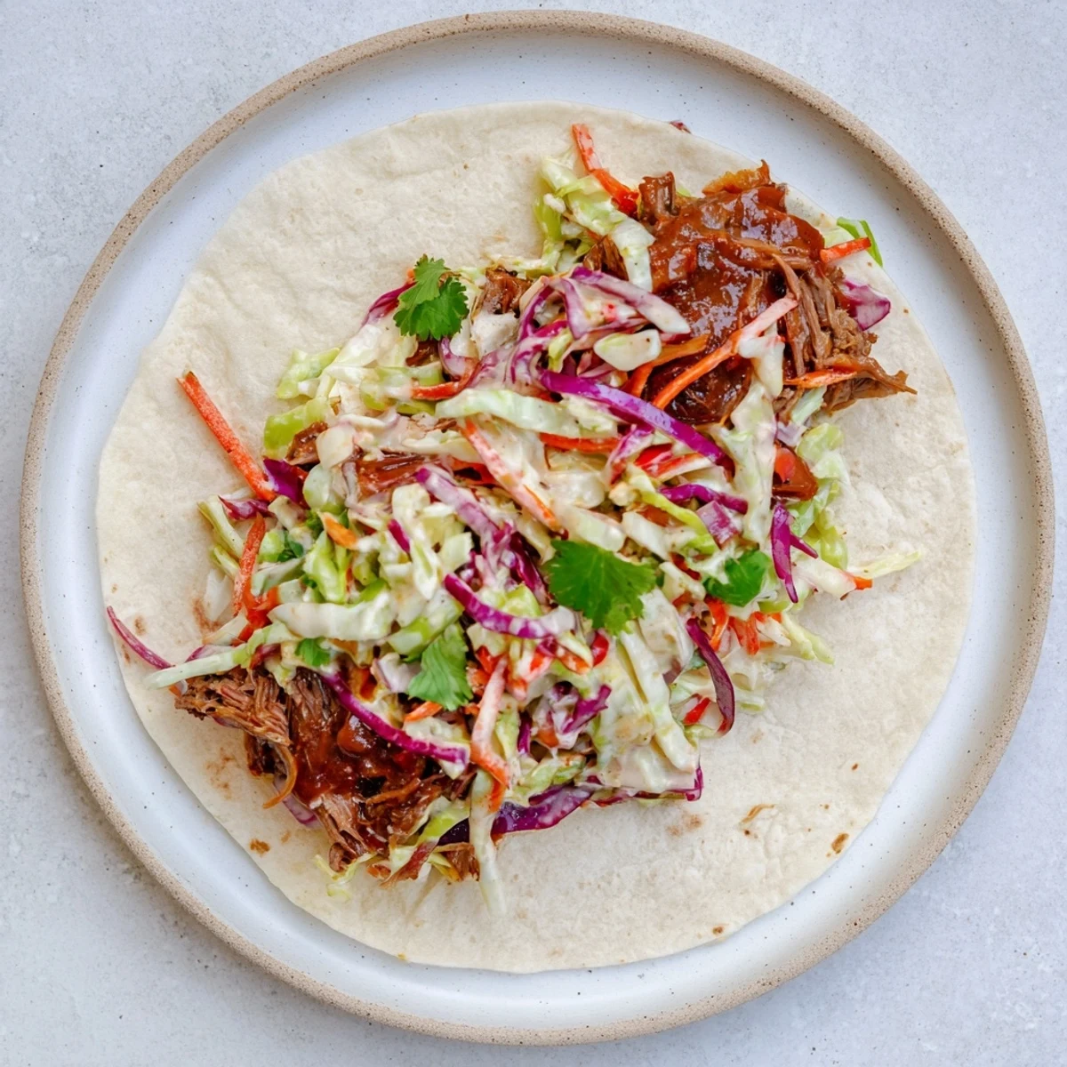 Hearty wrap piled high with slow-cooked beef in tangy BBQ sauce topped with crisp red and green cabbage slaw