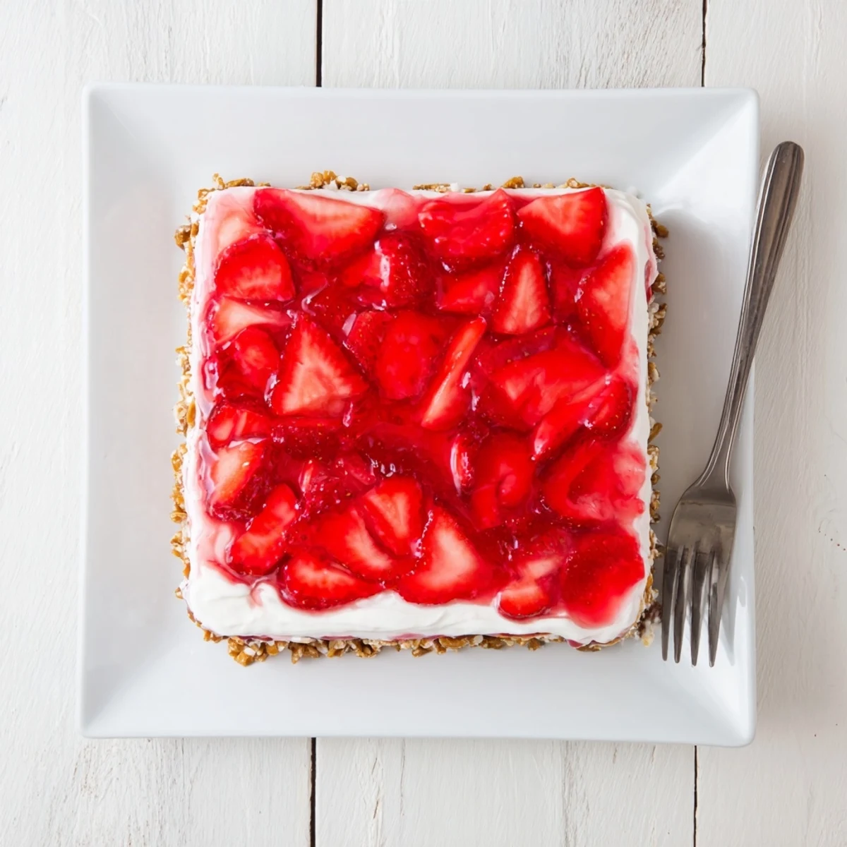 Fresh Strawberry Crackle Salad dessert with glistening strawberry gelatin layer and fluffy whipped cream topping arranged on white serving platter
