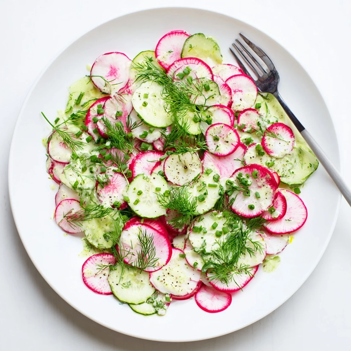 Colorful bowl of radish and cucumber salad with green onions and fresh herbs