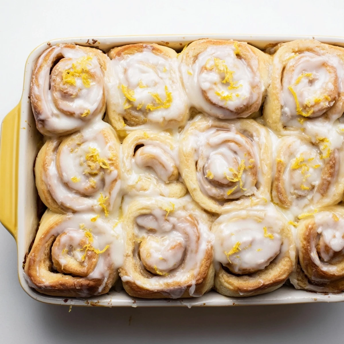 Soft lemon pastry rolls drizzled with zesty lemon glaze on a serving plate