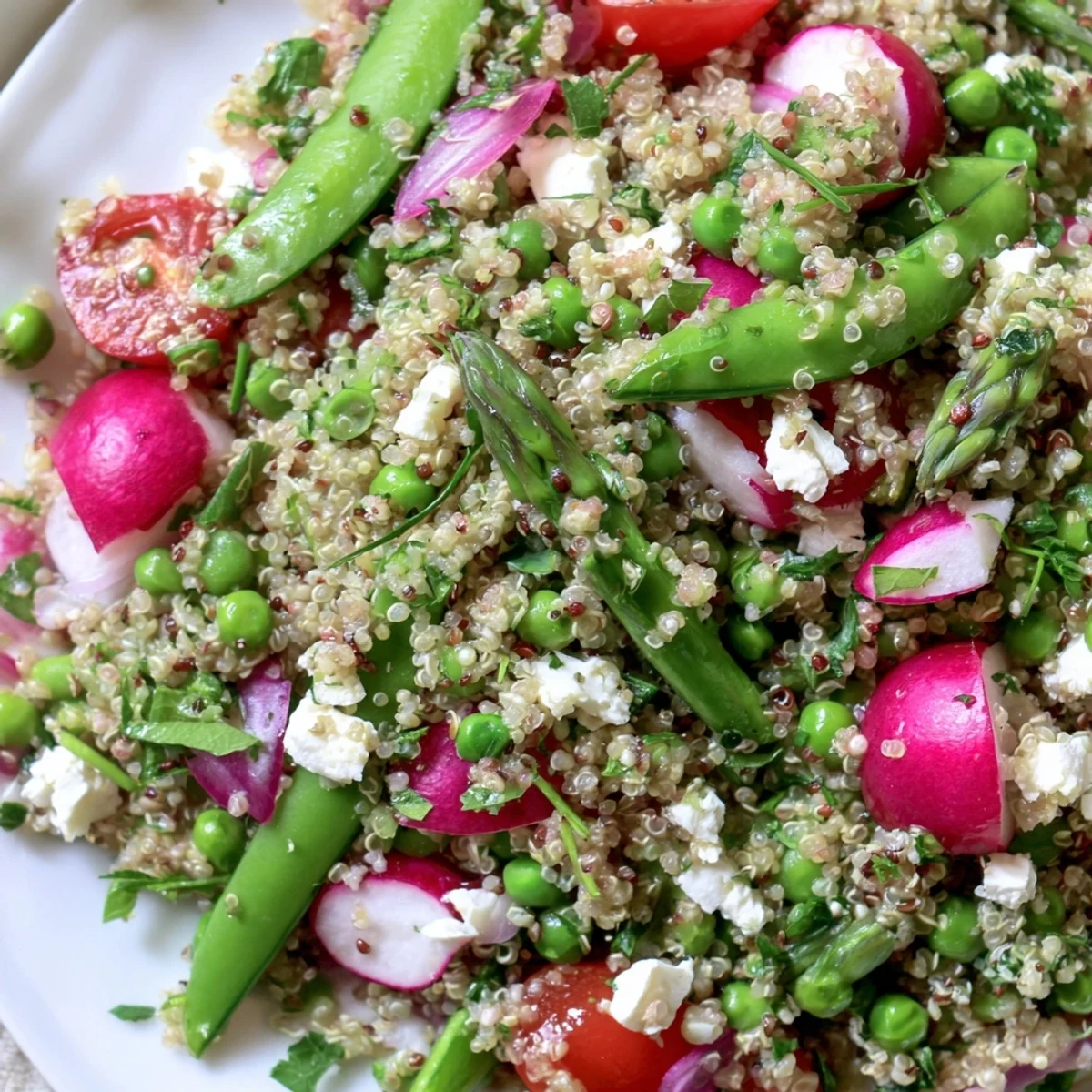 Colorful Spring Vegetable Quinoa Salad in a white bowl with fresh herbs and lemon vinaigrette