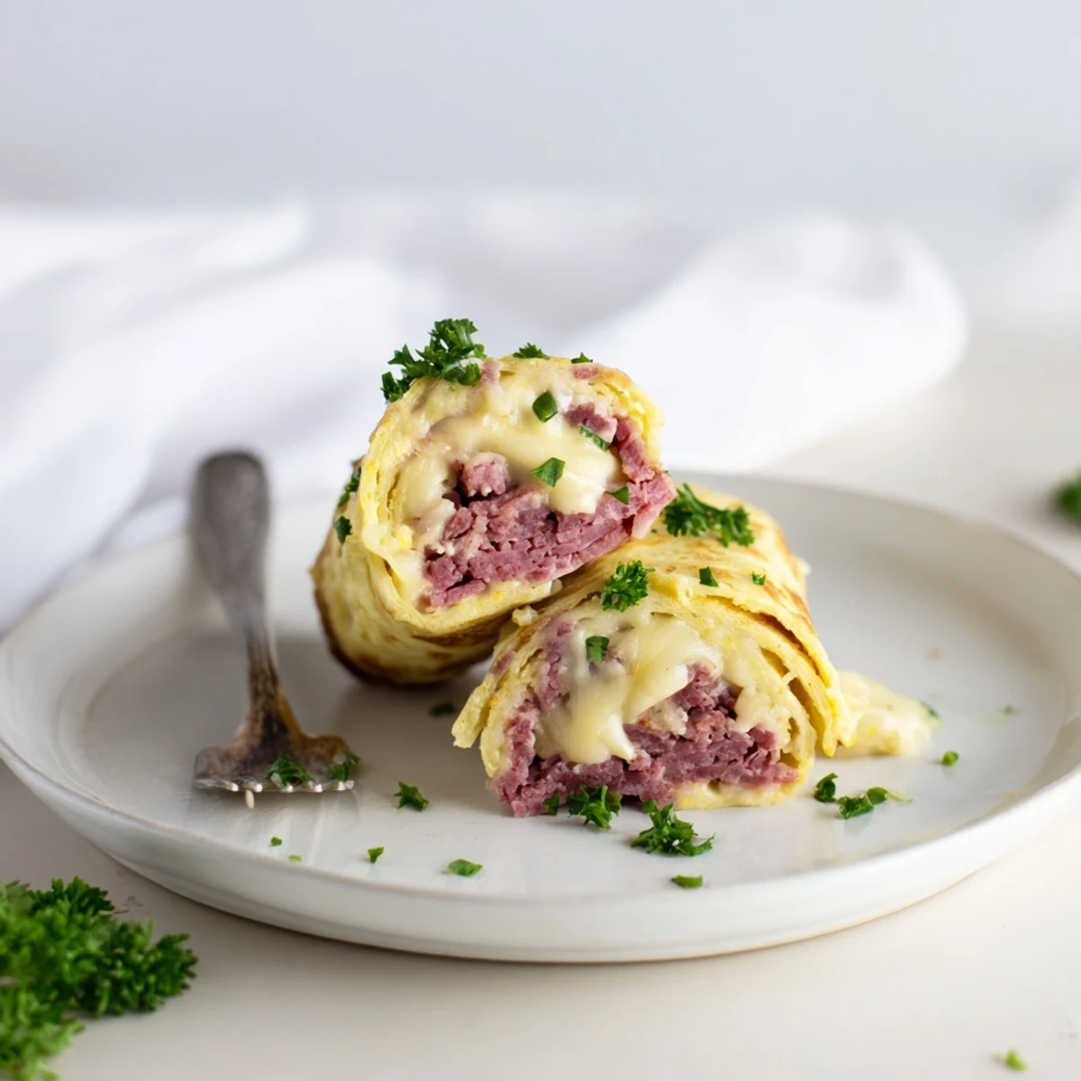 Golden Low Carb Reuben Egg Roll Ups filled with corned beef and melted Swiss cheese on a plate