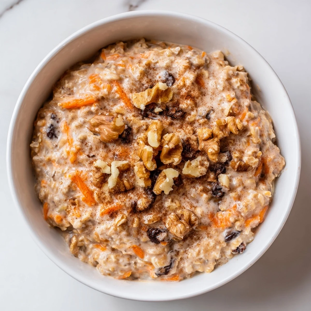 Carrot cake overnight oats with visible grated carrots, plump raisins, and a generous nutmeg dusting