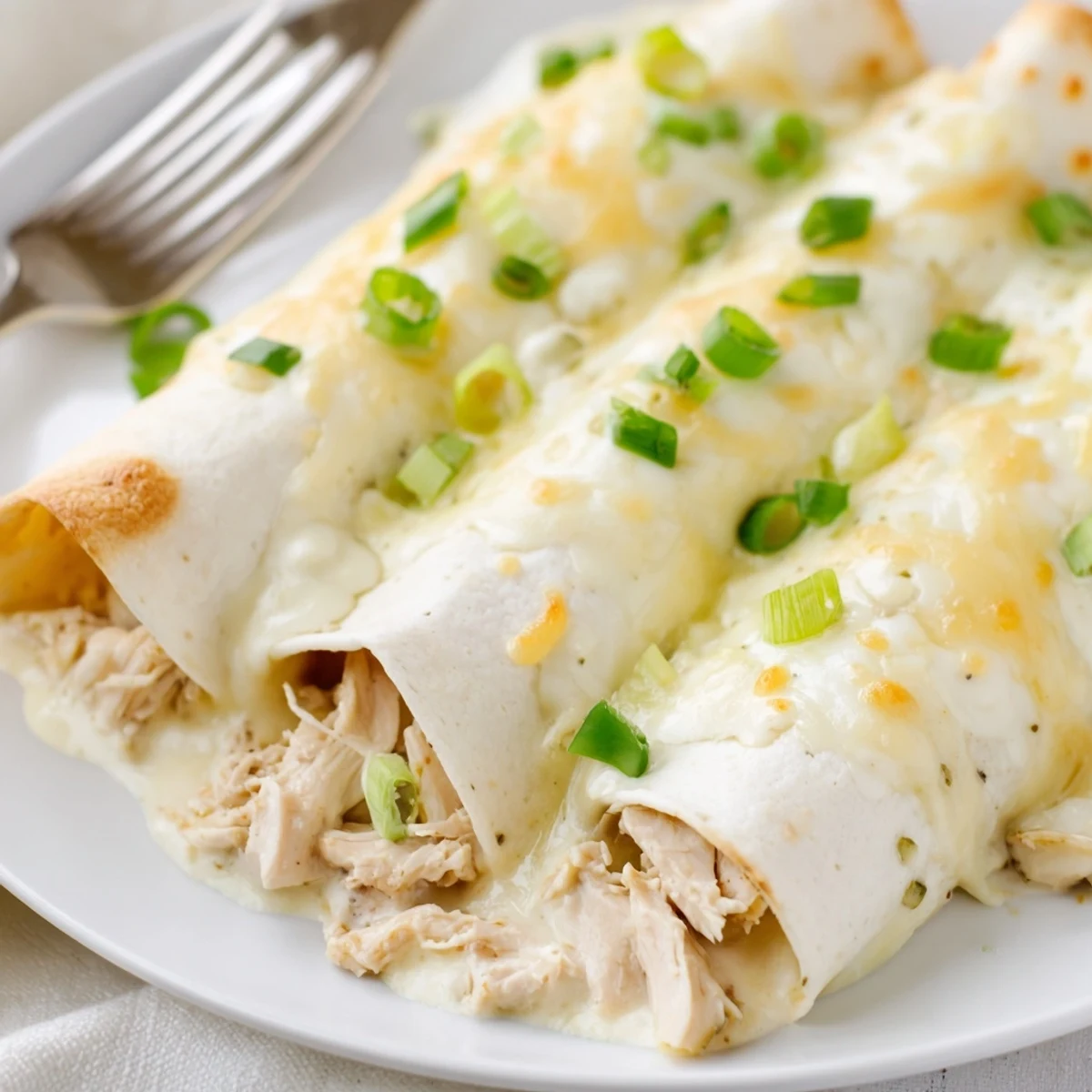 A comforting serving of Creamy White Chicken Enchiladas alongside crisp green salad.