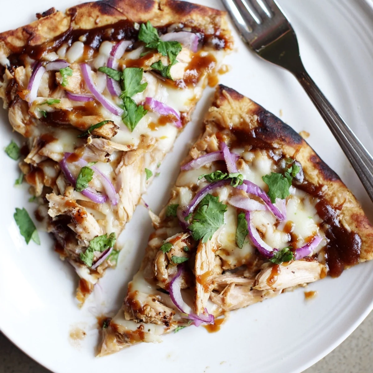 Slice of Grilled BBQ Chicken Pizza on cutting board, drizzled with sauce.