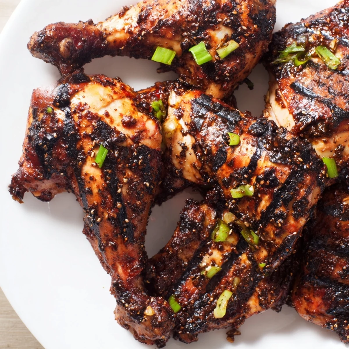 Golden brown Jamaican Jerk Chicken thighs resting on a wooden board with fresh thyme sprigs and lime wedges