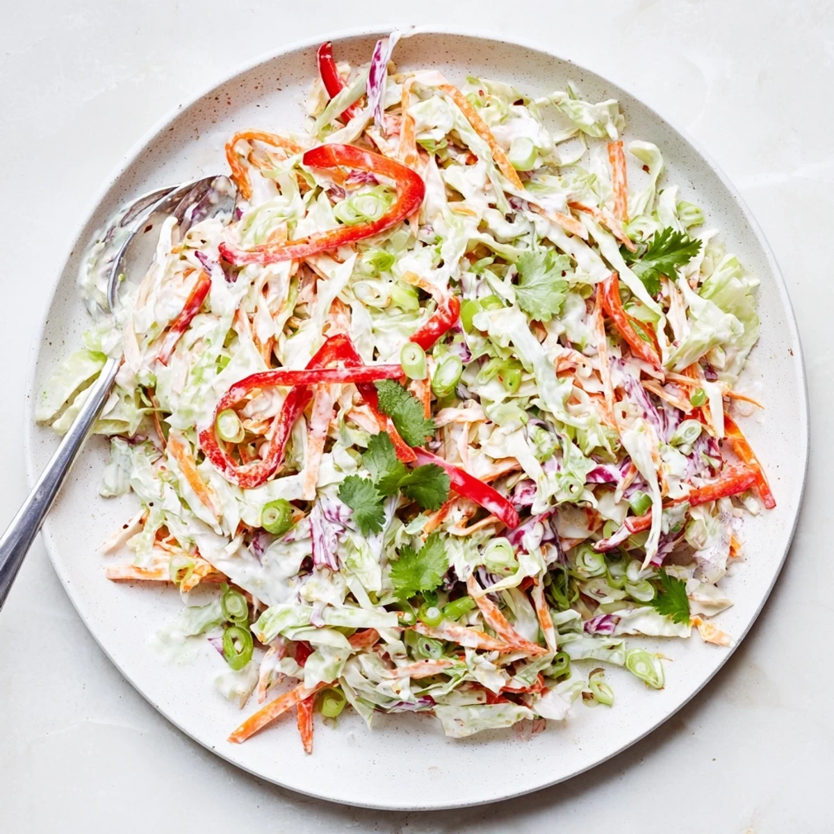 Refreshing summer slaw salad with shredded carrots and bell peppers coated in tangy yogurt dressing