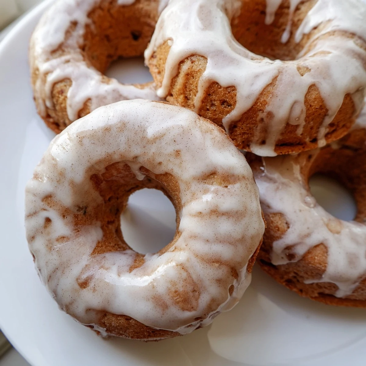 Freshly baked banana bread donuts with cinnamon sugar coating on a white wire rack