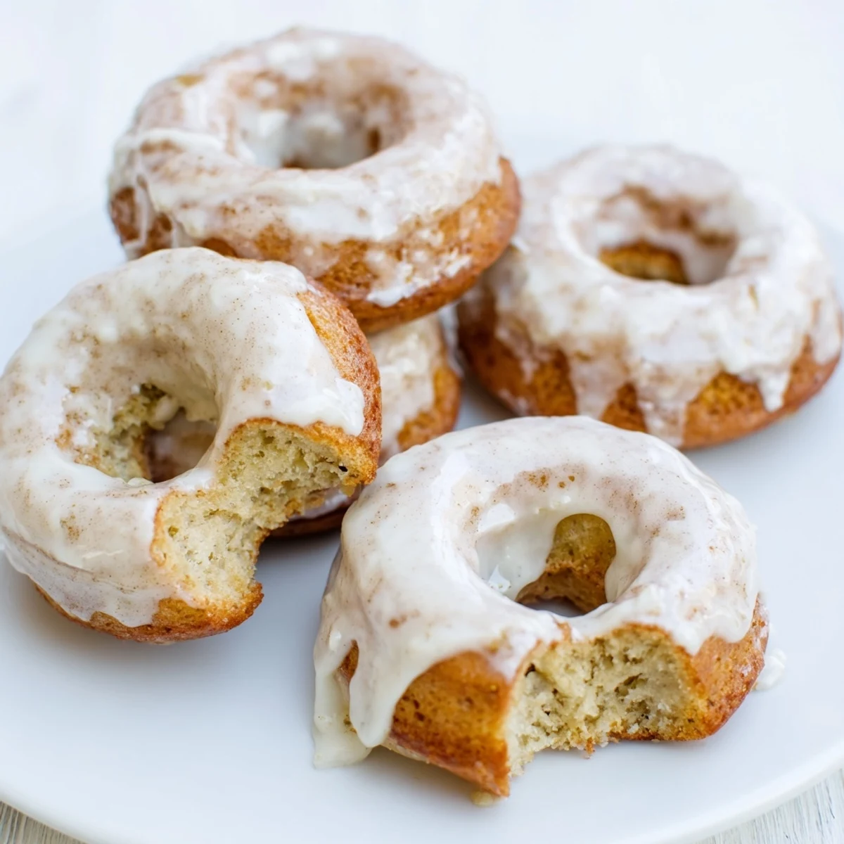 Soft moist banana bread donuts stacked on a wooden cutting board ready for serving