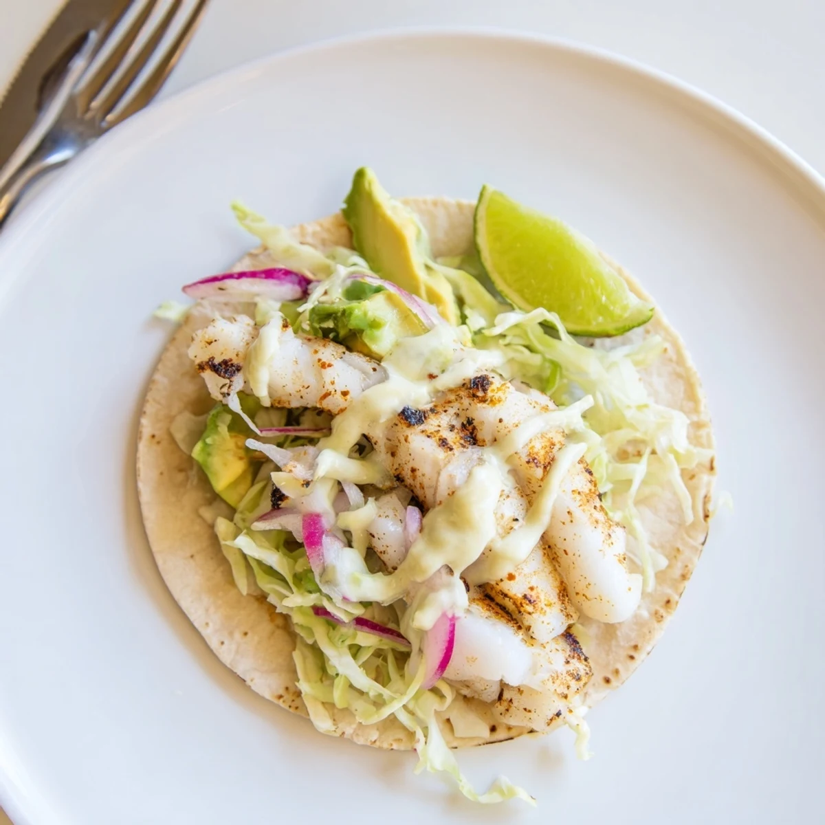 Baked Cod Fish Tacos with Creamy Cilantro Lime Sauce on warm tortillas, flaky cod