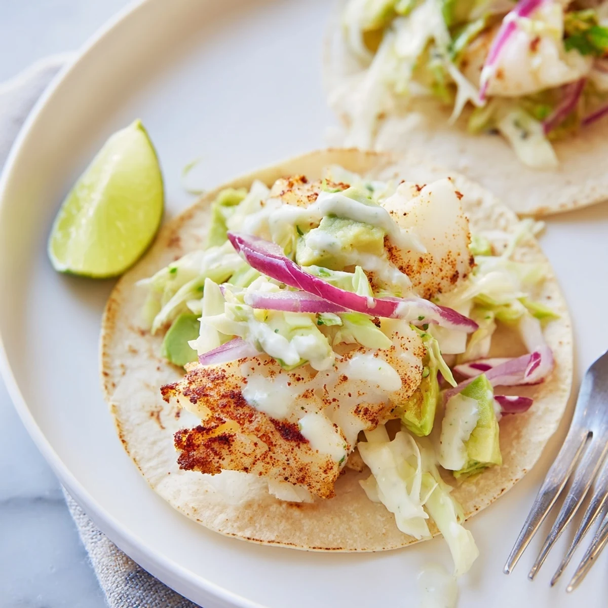 Baked Cod Fish Tacos with Creamy Cilantro Lime Sauce topped with crisp slaw