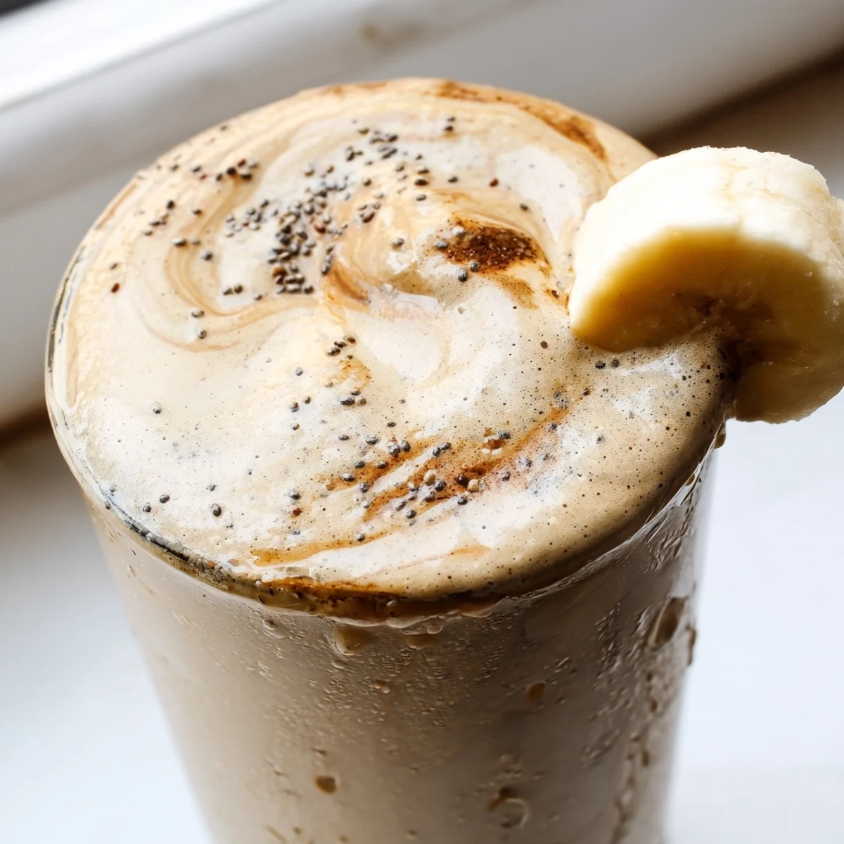 Thick banana protein coffee smoothie topped with a sprinkle of ground cinnamon