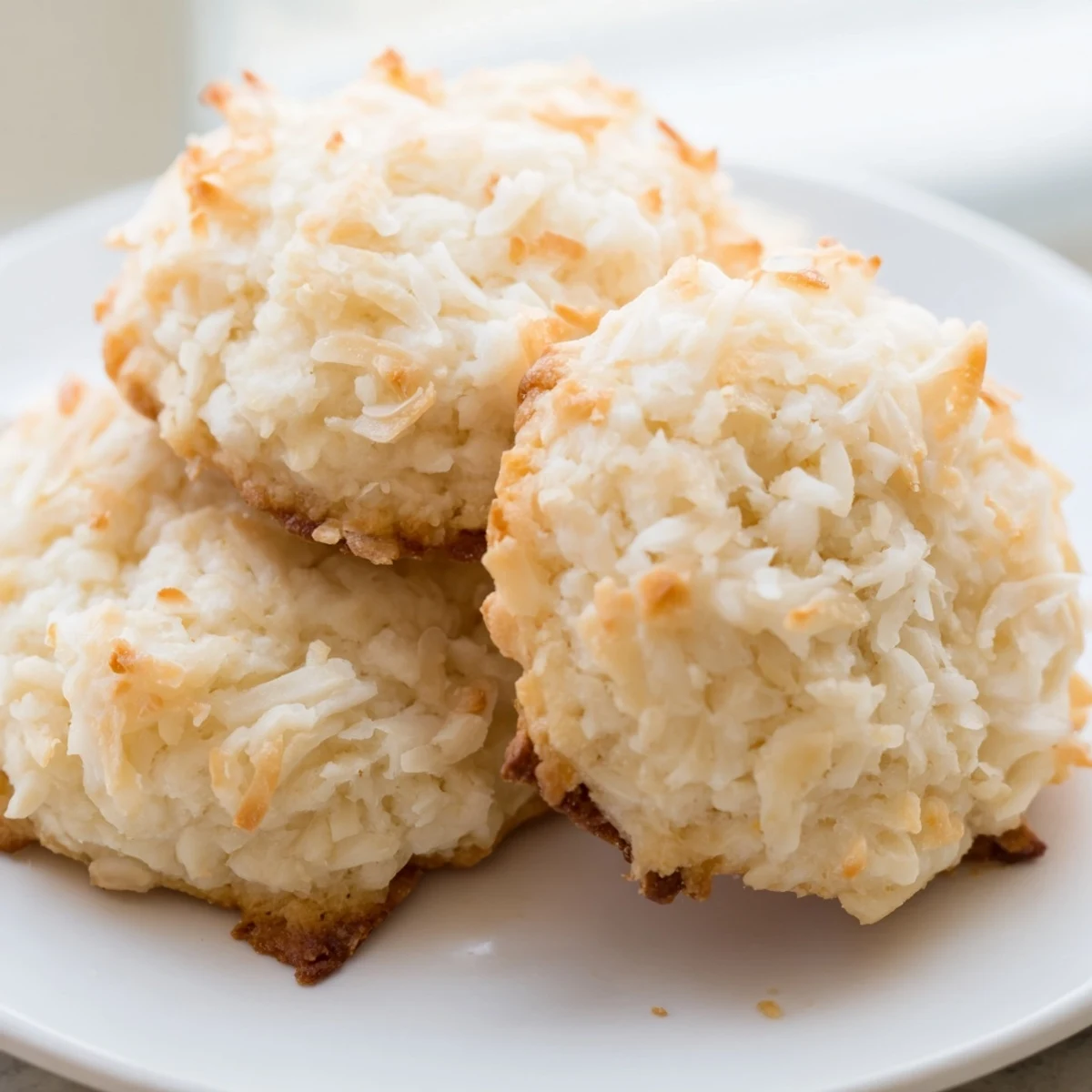 Warm soft and buttery coconut cookies arranged on a rustic parchment-lined baking sheet