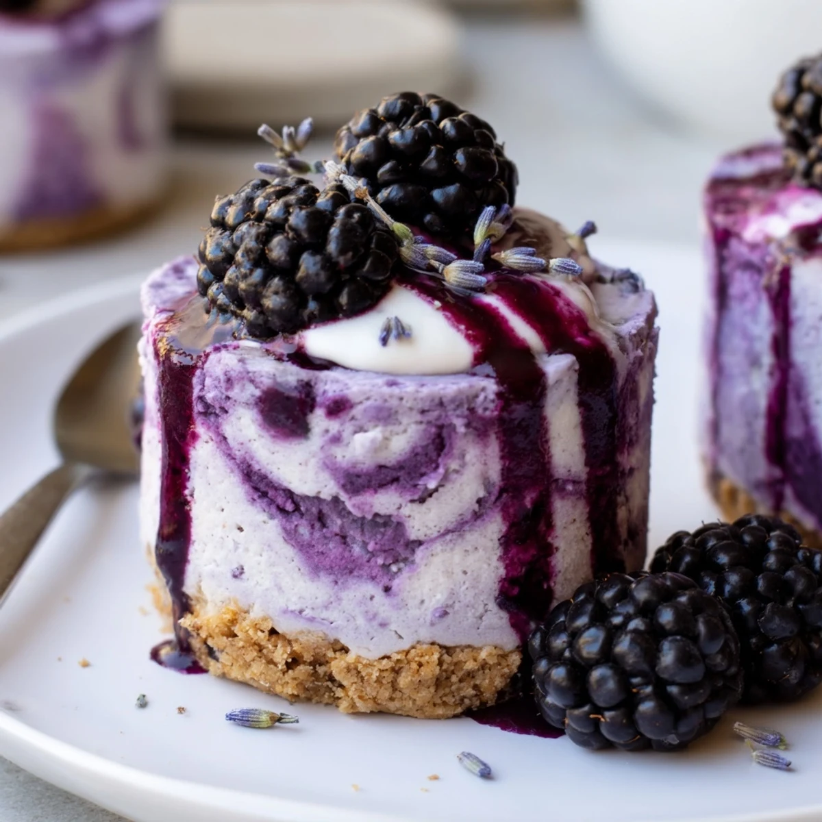 Velvety blackberry lavender cheesecakes with buttery graham crust drizzled in berry sauce