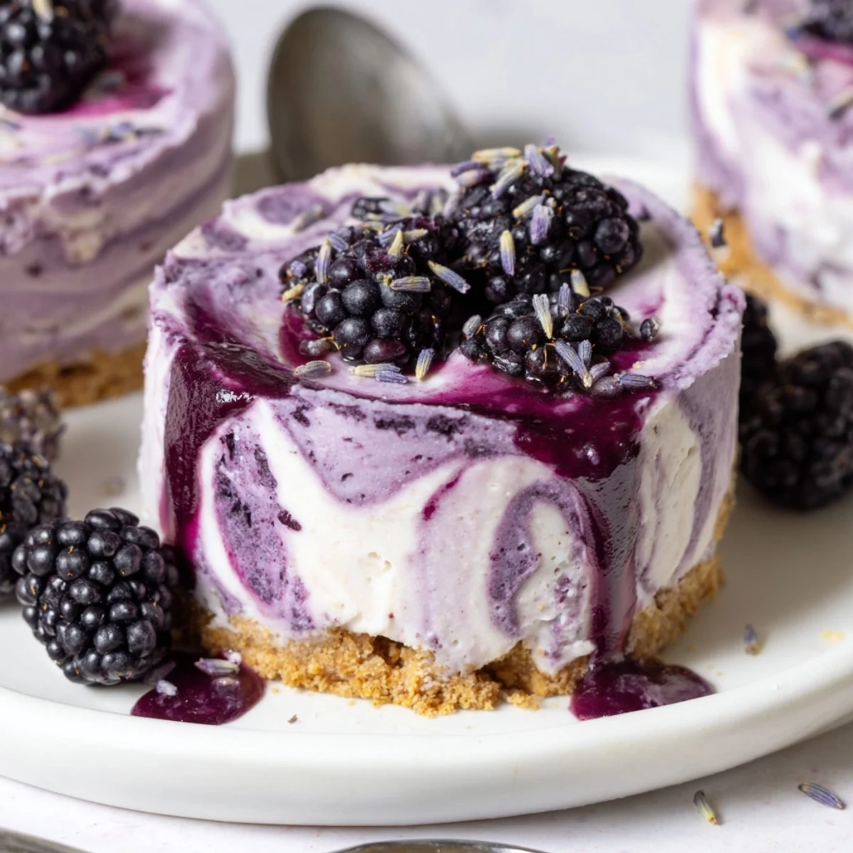 Individual blackberry lavender cheesecakes with swirls of purple filling on cookie bases