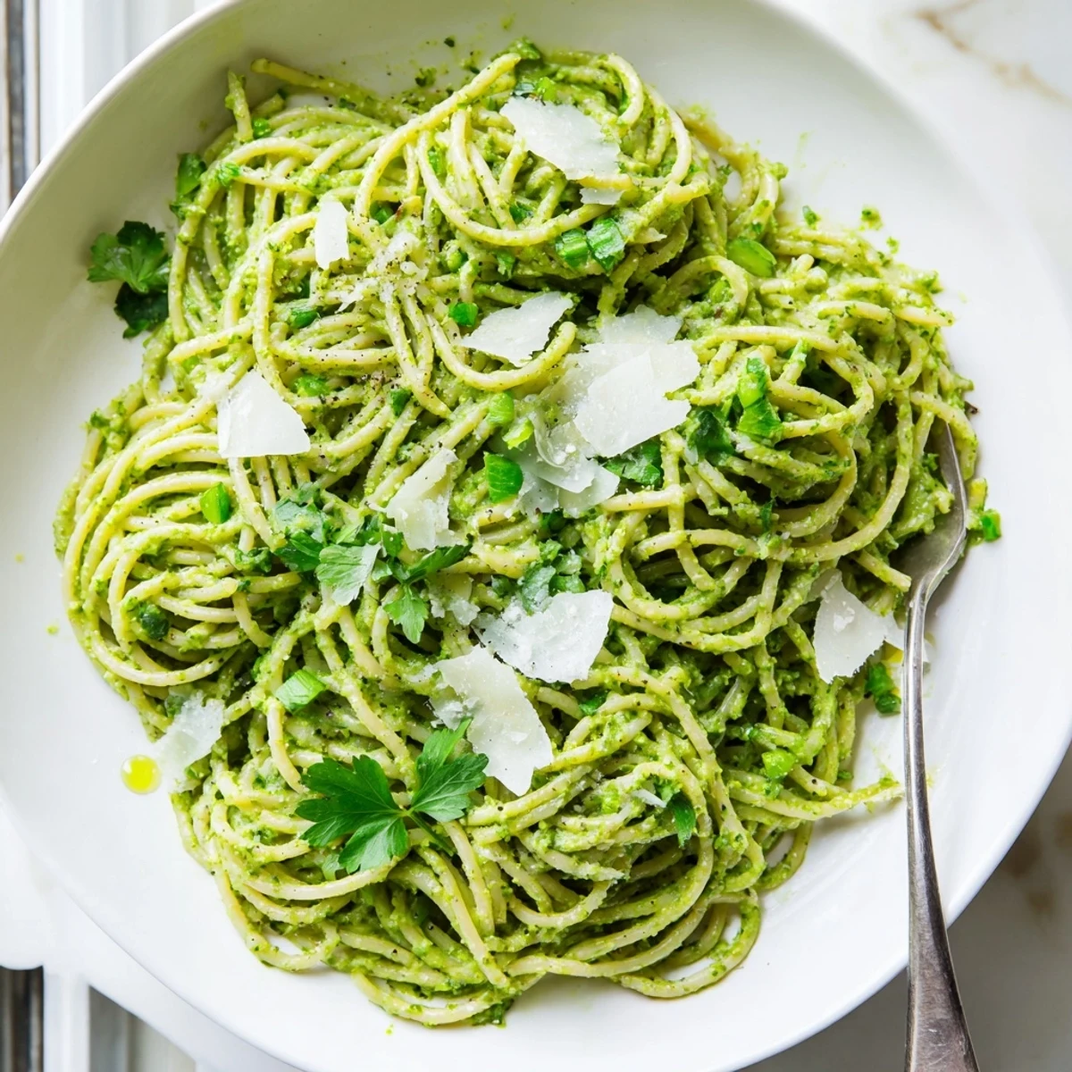 Vibrant green goddess pasta sauce topped with fresh herbs and a dusting of Parmesan cheese