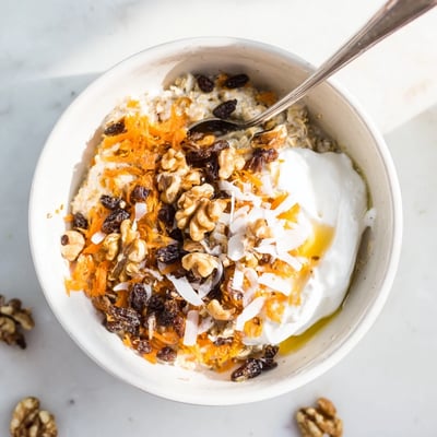 Chilled Carrot Cake Overnight Oats served with a spoon, featuring crunchy pecans and warm cinnamon spices for breakfast.
