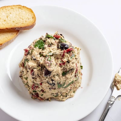 A rustic bowl of Italian Style Olive and Cheese Spread with fresh basil
