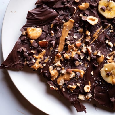 Dark chocolate banana bark drizzled with peanut butter and sprinkled with crushed almonds