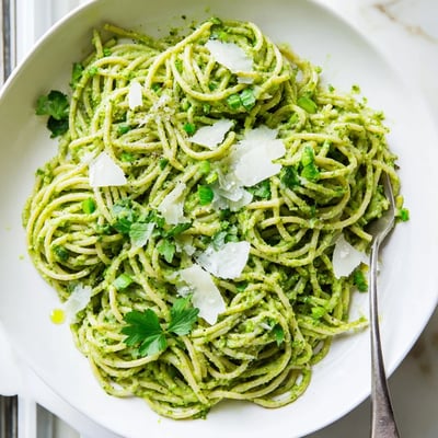 Vibrant green goddess pasta sauce topped with fresh herbs and a dusting of Parmesan cheese